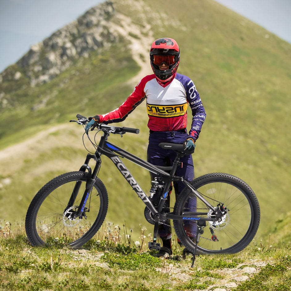 Person in mountain bike gear standing with a bicycle in a grassy outdoor setting